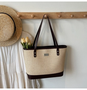 Macro detail of the woven texture and dark brown leather straps on the beige tote bag