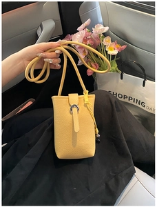 Detail of yellow lychee leather mini crossbody bag with silver buckle in car interior