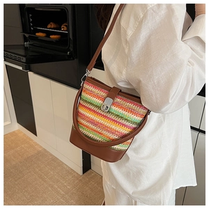 Rainbow woven bucket bag with brown leather strap and metal buckle in a kitchen setting