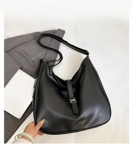 Detail of minimalist black PU leather tote bag with gold metal buckle and shoulder strap