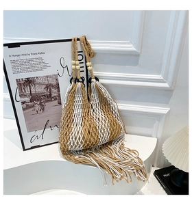 Close-up of woven beach tote bag featuring cotton rope tassels and wooden bead details