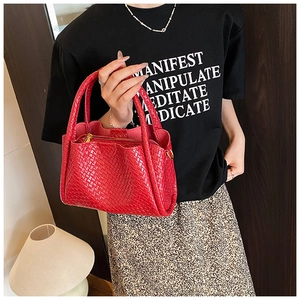 Détail du sac cabas rouge tressé montrant la texture en damier et les poignées solides