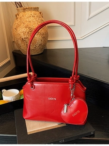 Sac seau rouge élégant en cuir avec pendentif cœur et bandoulière dans un décor chic