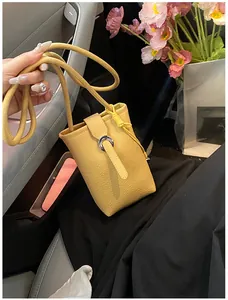 Detail of yellow litchi grain leather mini phone bag with silver ring buckle and strap