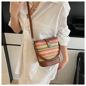 Detailed close-up of colorful rainbow woven bucket bag with brown leather trim and metal clasp