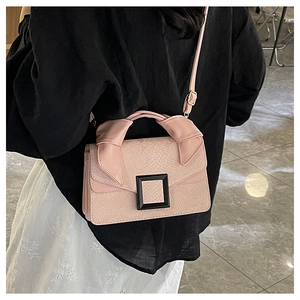 Detail of pink snakeskin pattern handbag with black buckle shown on a model