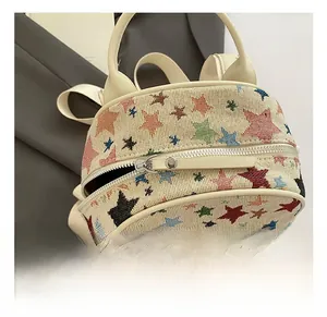 Close-up of beige canvas backpack with colorful star embroidery and silver zipper