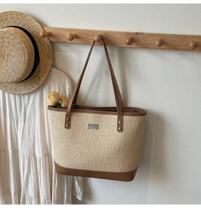 Detail of the woven tote bag showing the textured straw fibers and brown leather straps
