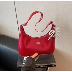 Detail of red crescent bag with silver zipper, logo print and pearl bow charm