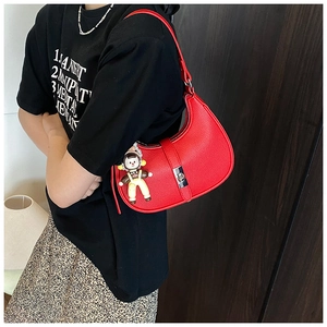 Side view of red pebbled leather hobo bag with silver buckle and cute cartoon charm