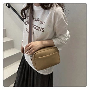 Detail of khaki litchi texture PU crossbody bag featuring adjustable wide strap