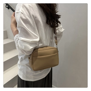Detail view of khaki pebble grain leather crossbody bag with wide shoulder strap