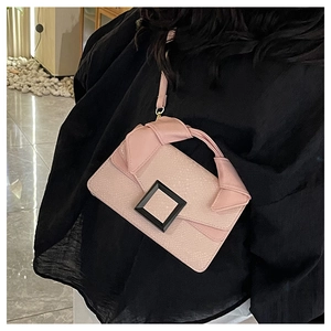Détail du sac en cuir rose avec boucle noire et poignée décorative en nœud de soie