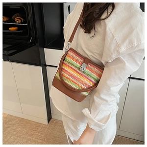 Detail of rainbow straw crossbody bag with brown leather trim and silver metal twist lock