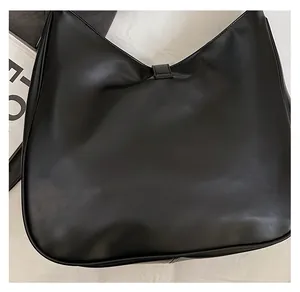 Detail of black leather hobo bag with magnetic buckle on white fabric background