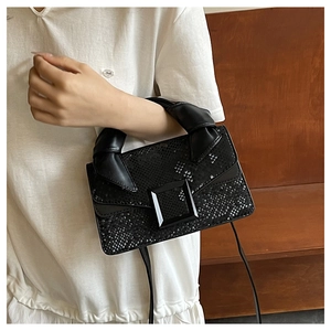 Close-up of black faux leather handbag with snake pattern texture and knotted handle