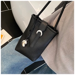 Detail of a black bucket phone bag with silver horseshoe buckle and litchi texture