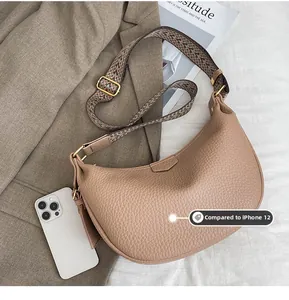Close-up of khaki dumpling bag with wide jacquard strap compared to iPhone 12 for size