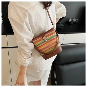 Detailed shot of rainbow woven straw bucket bag with brown leather handles and metal clasp