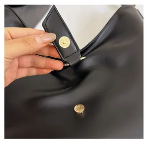 Close-up of a light gold magnetic buckle on a premium black leather tote bag