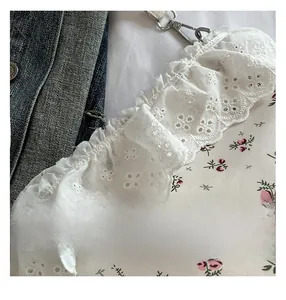 Close-up of floral drawstring bag featuring white lace edges and durable metal hook