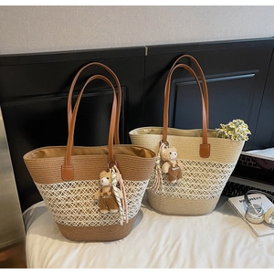 Macro detail of large woven straw tote bags featuring white hollow mesh and bear charm