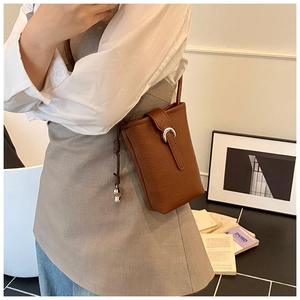Détail du sac seau pour téléphone en cuir marron foncé avec texture grainée et fermoir