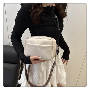 Close-up of off-white lychee pattern PU crossbody bag with wide brown striped strap