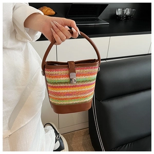 Detail view of rainbow woven bucket bag with brown leather trim and metal clasp closure
