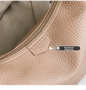 Detail of high-quality lychee grain leather texture and gold zipper on a beige bag