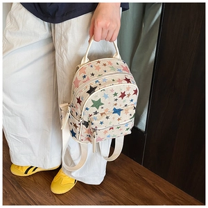 Detail shot of mini canvas backpack with colorful star patterns and dual zipper pockets