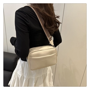 Detail of cream lychee pattern leather crossbody bag with striped wide fabric strap