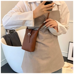 Détail d'un sac à téléphone en cuir marron grainé avec boucle en fer à cheval argentée