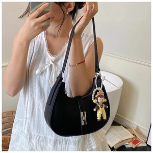 Detail of black pebbled leather half-moon bag with silver clasp and cute cartoon pendant