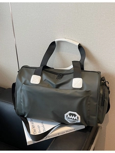 Sac de voyage en nylon imperméable vert olive avec bandoulière sur un canapé en cuir noir