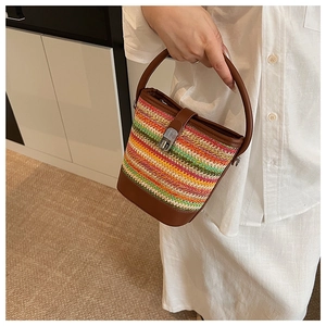 Detailed shot of a rainbow woven bucket bag with brown leather handles and silver twist lock