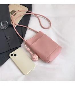 Pink lychee texture crossbody phone bag with front pocket and woven charm detail
