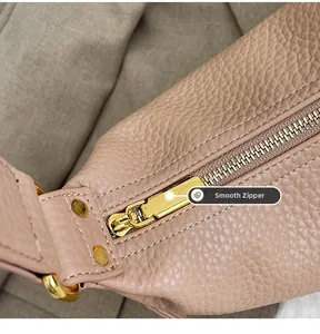 Macro shot of smooth golden zipper and lychee grain leather on a pink dumpling bag
