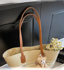 Detail of woven straw tote bag with brown leather shoulder strap and plush bear charm