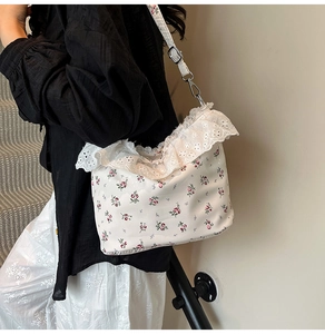Detailed view of floral shoulder bag with white lace trim and adjustable strap