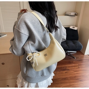 Close-up of beige moon bag with premium PU texture and a pearl bow charm detail