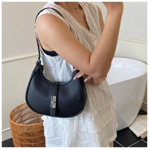 Detail view of a black lychee texture leather shoulder bag with a silver twist lock buckle
