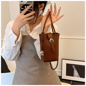 Detail view of brown lychee grain leather bucket bag with silver horseshoe buckle closure