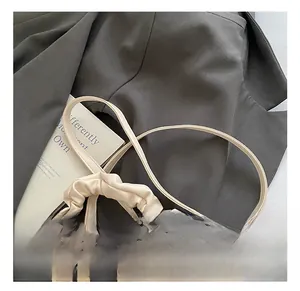 Detail of cream pleated leather handle and adjustable shoulder strap on a modern handbag