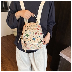 Mini canvas backpack with colorful star print and dual zipper pockets on female model