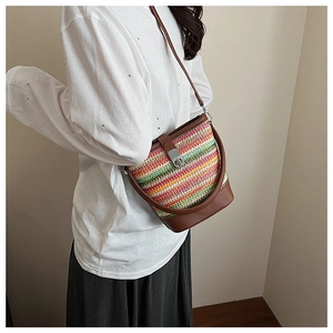Detail of rainbow woven bucket bag featuring brown leather trim and metal twist lock