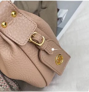 Macro detail of beige pebble leather bag featuring gold hardware and logo pendant