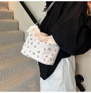 Detail showing red floral pattern on canvas shoulder bag with delicate lace trim