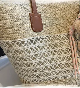 Detailed close-up of woven straw texture with hollow mesh pattern and pink tassel charm