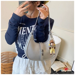 Detail of silver pebble leather crescent bag with metal buckle and cute plush charm